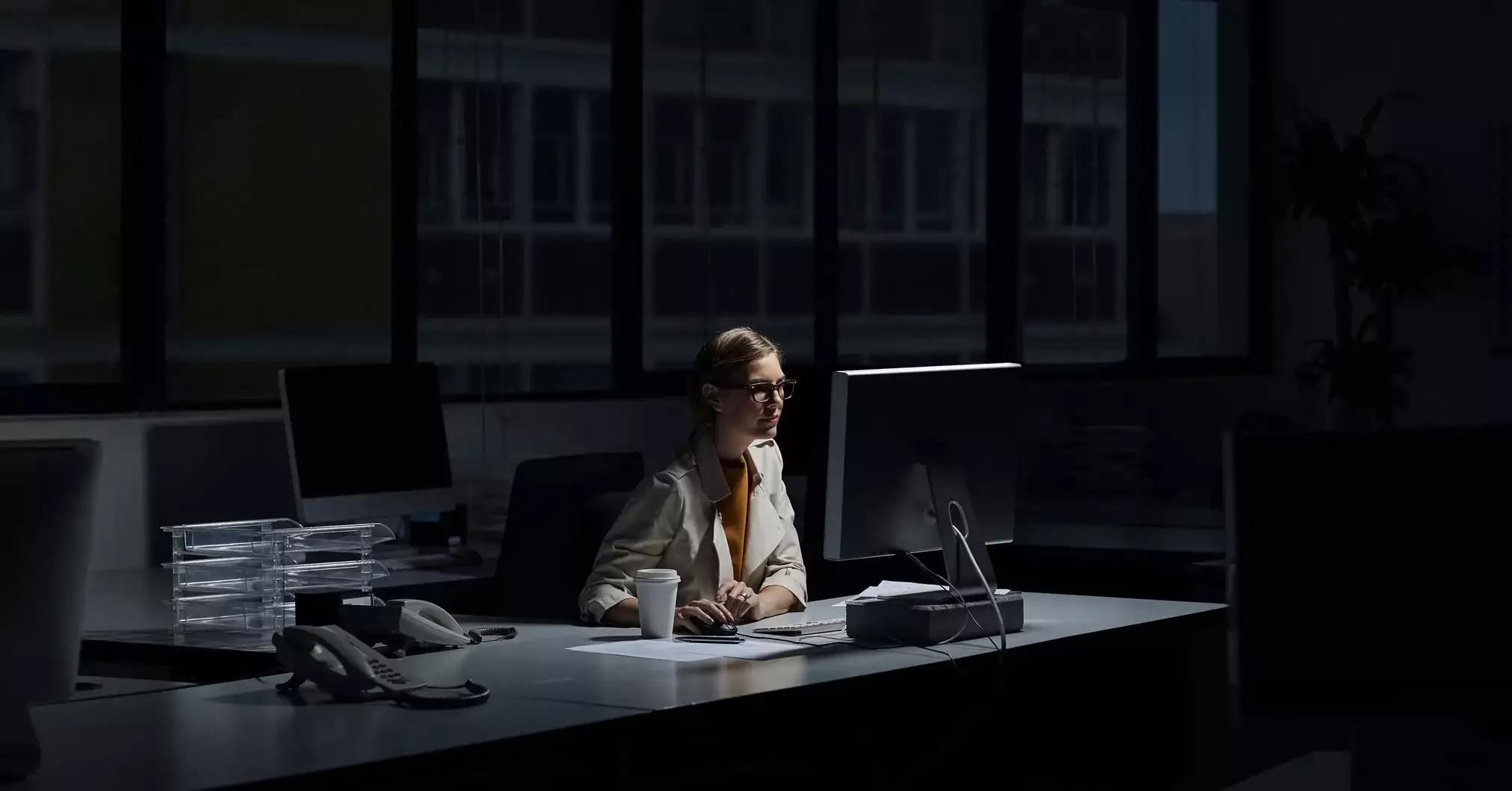 Młoda kobieta przed komputerem w ciemnym biurze